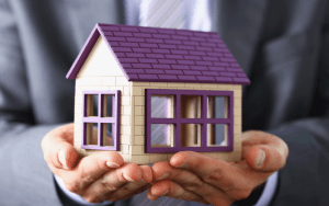 a person holding a house - mortgage protection insurance