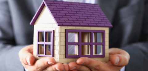 a person holding a house - mortgage protection insurance